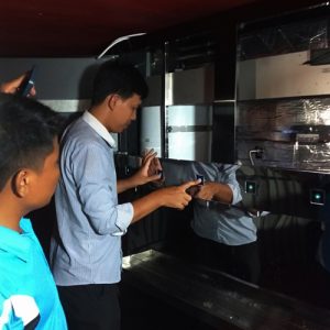 Technician inspecting and testing touch-sensor dispensing controls on commercial water filtration station.