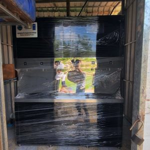 Commercial stainless steel drinking water filtration unit wrapped for protection with UNDP and Coca-Cola project plaque.